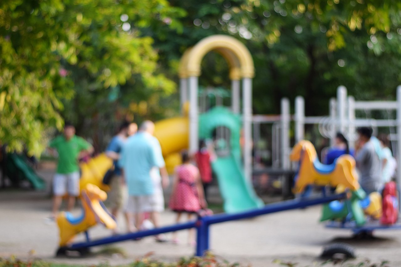 Colorful-playground-with-children-and-parents-in-park-(blur-background
